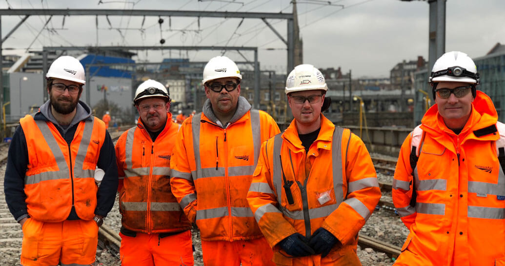 five workers on track wearing personal protective equipment (PPE)