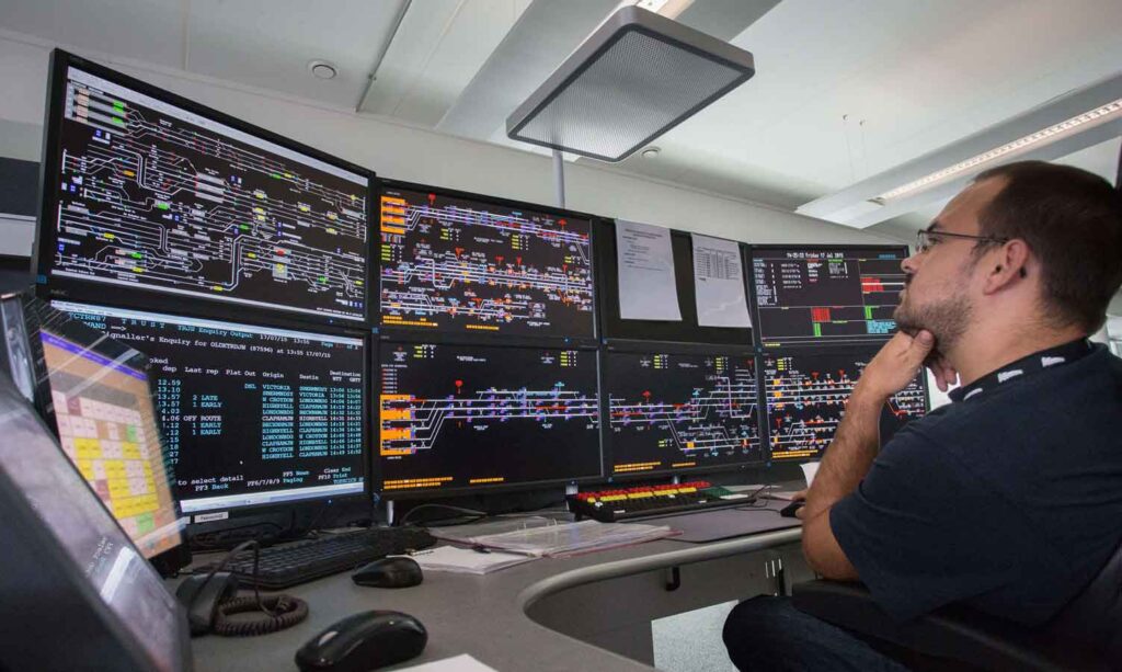 A signaller working with digital signalling screens at Three Bridges rail operating centre (ROC)