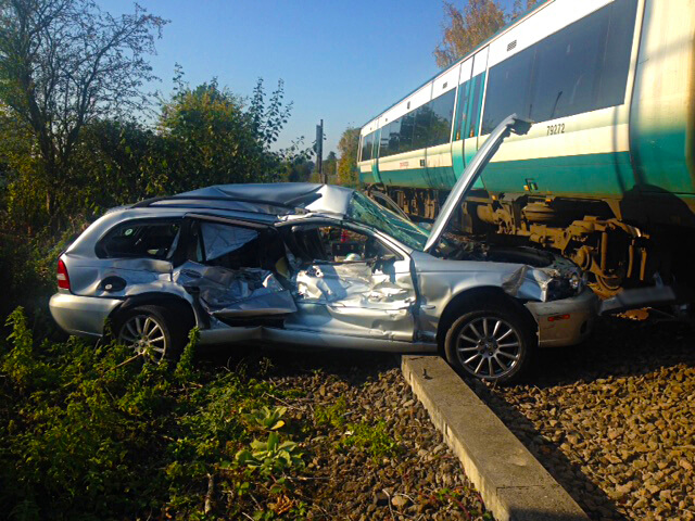 car wreckage and train at a level crossing