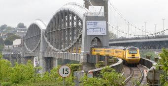 A yellow engineering train crosses the Royal Albert Bridge, daytime