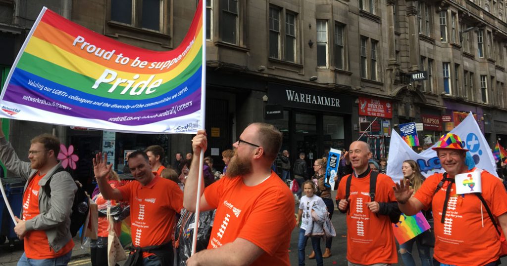 Network Rail employees taking part in a Pride event holding a rainbow flag
