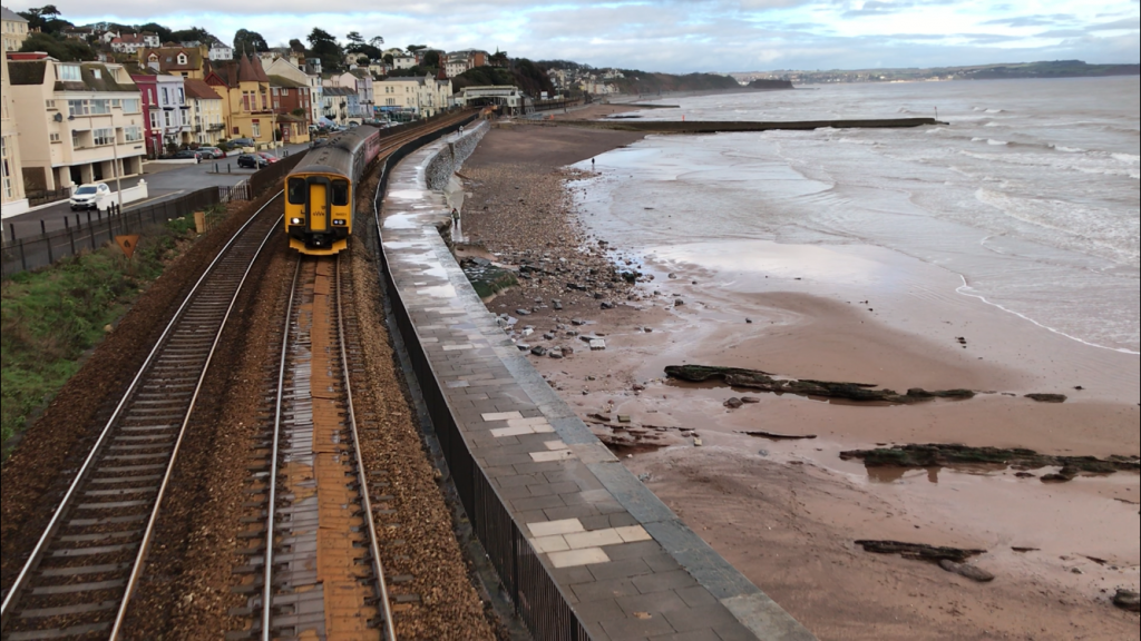 Train travelling on tracks adjacent to Dawlish sea wall 