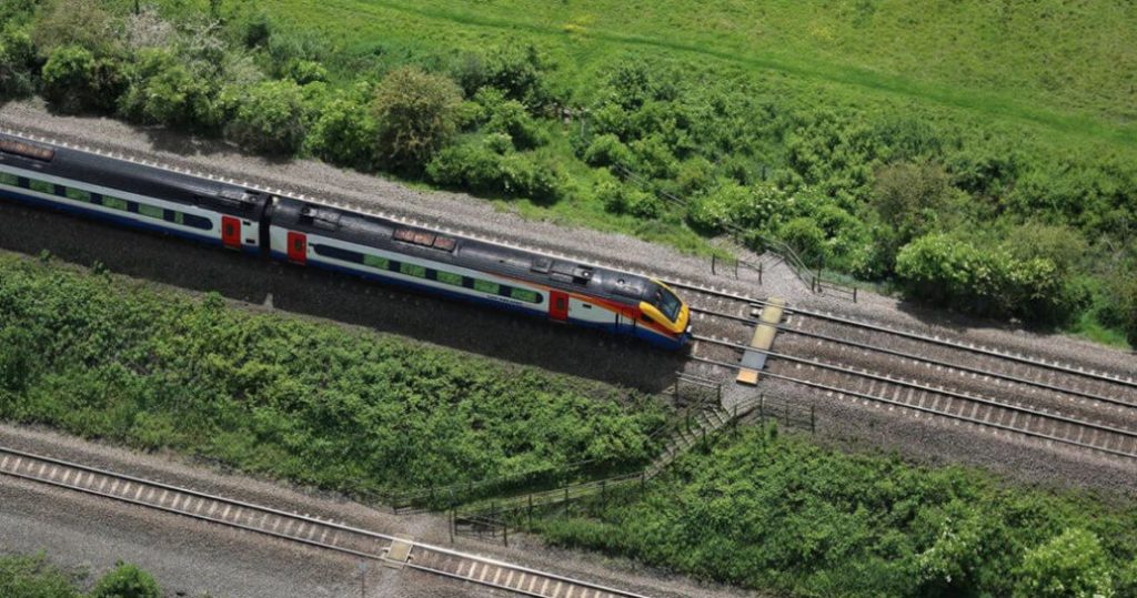 A train travels between green embankments, daytime.