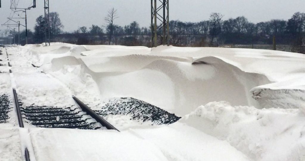 Railway tracks mostly covered in very deep snow, daytime