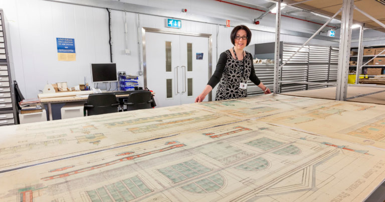 Archivist Vicky Stretch stands in front of huge original railway station drawings at the Network Rail archive