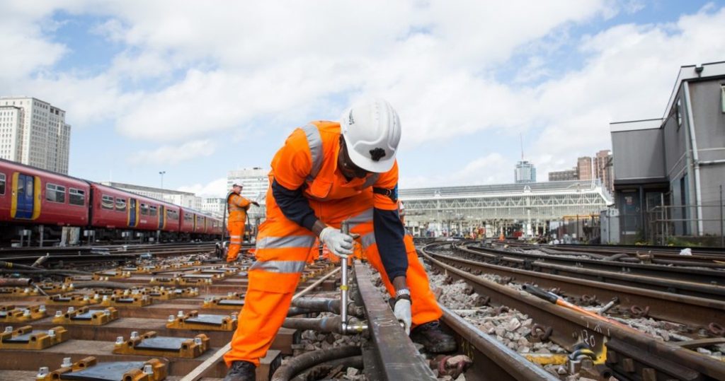 A railway worker tending to the track outside London Waterloo station, daytime