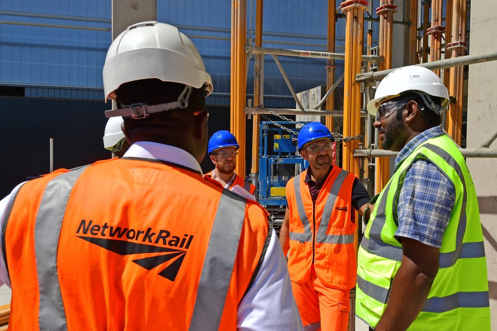 Railway workers talking whilst wearing PPE, goggles and hard hats