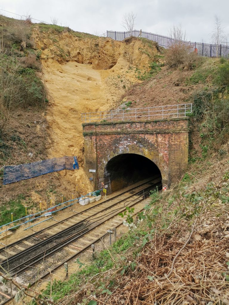 Portrait view of the railway and railway tunnel next to the embankment where the cave in Surrey was found, daytime