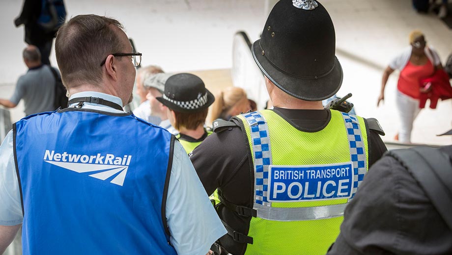 Network Rail employee and British Transport Police officer on escalator at station.