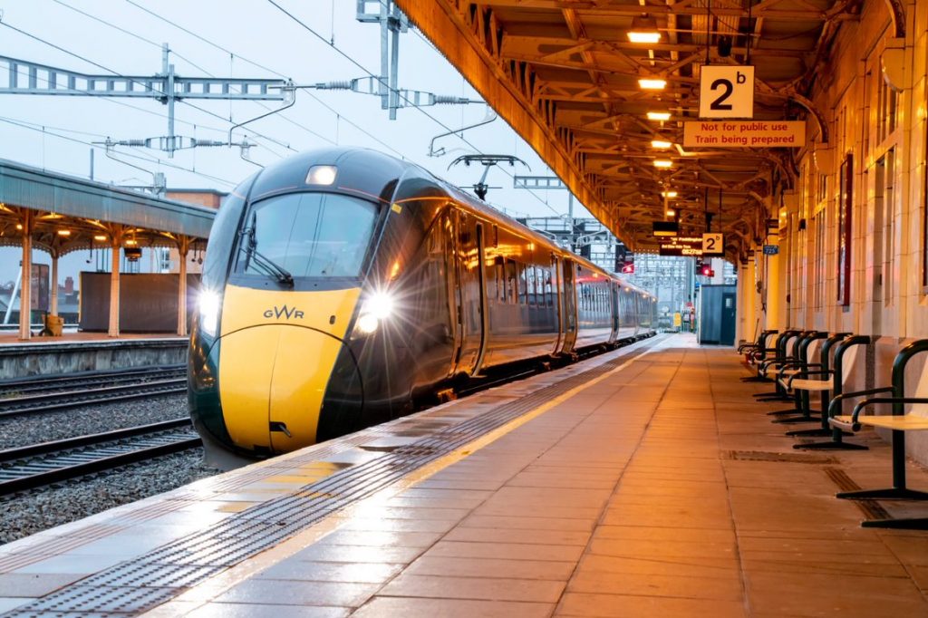 A Great Western Railway train calls at a station, dusk