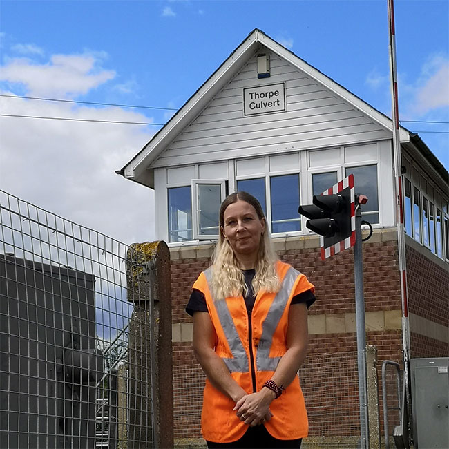 Debbie, the signaller, standing near a signal box