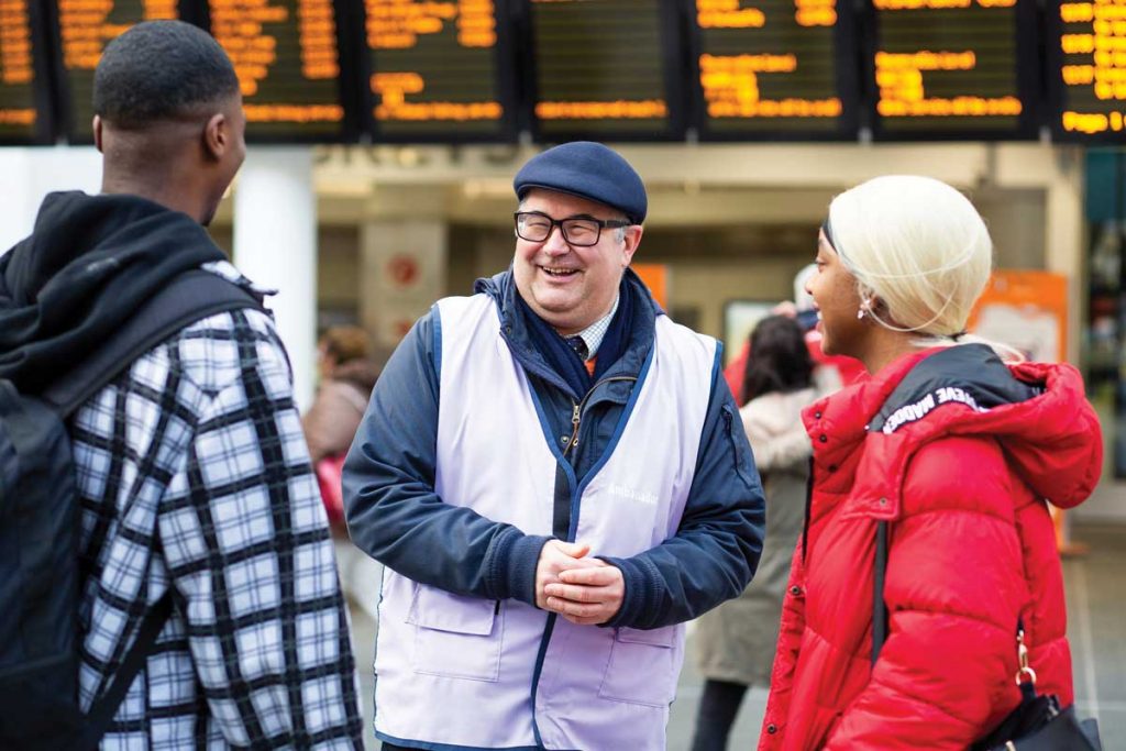 Member of station staff with passengers at a station