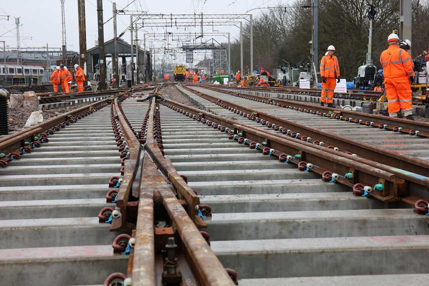 Close up of rail tracks with engineers working in the background