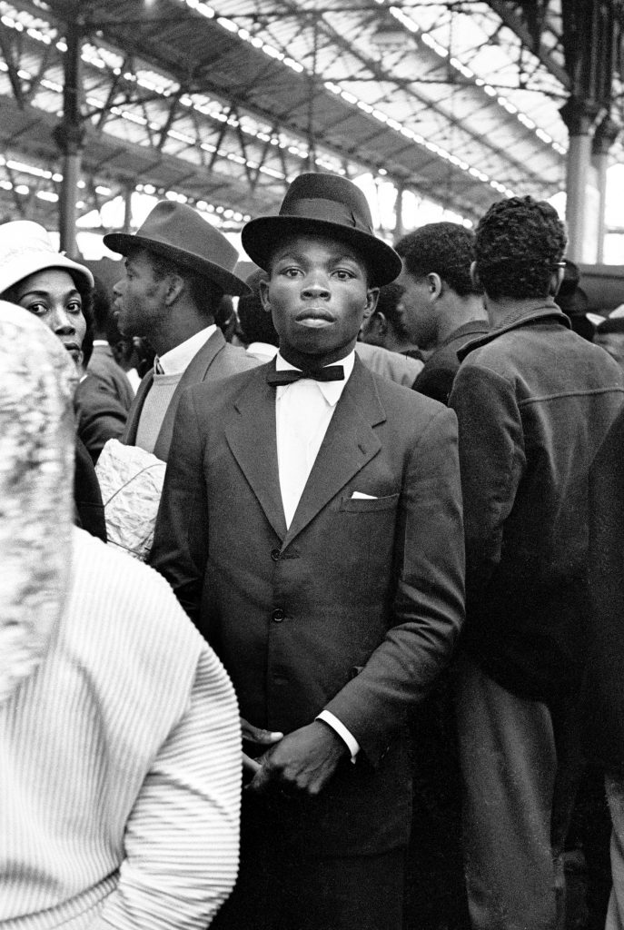 A black and white photograph from the 1960s of a man at London Waterloo station 