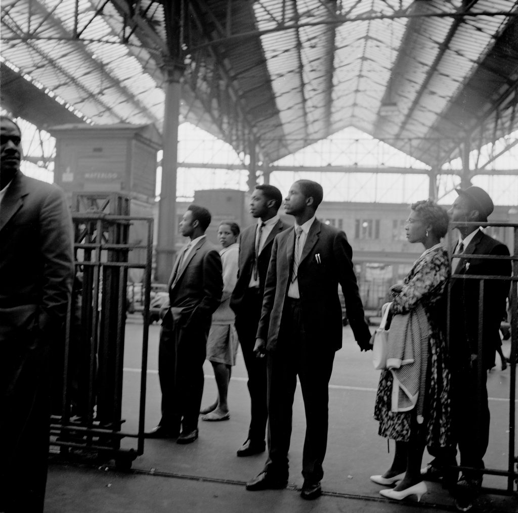 Black and white photograph by Howard Grey of the Windrush Generation arriving at London Waterloo station