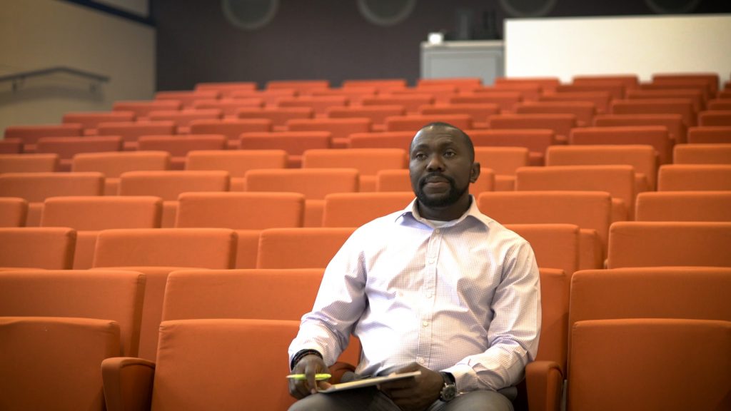 Adelaja, our engineering apprentice sitting with a notepad in a large classroom