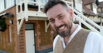 Headshot of presenter Tim Dunn outside a traditional signal box, daytime