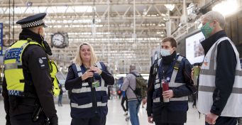 A police officer and station staff chat on the concourse at London Waterloo station