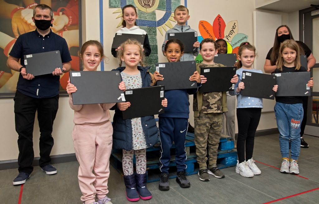 School children and teachers holding laptops donated by Network Rail