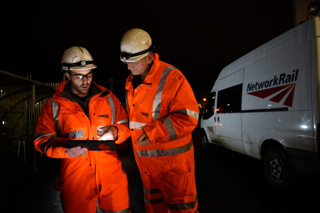Two Network Rail maintenance workers in full PPE looking at an iPad