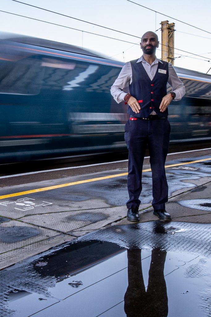 Hussain Master, an Avanti West Coast train manager, on a platform with a train passing, daytime