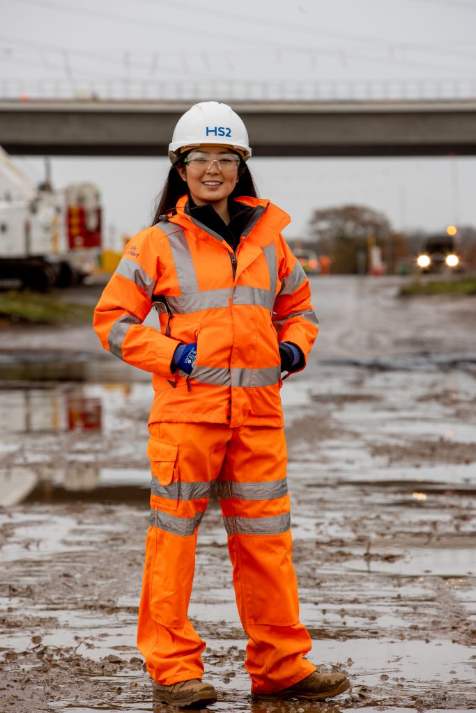 Railway worker Laing O’Rourke in PPE with HS2 hard hat in front of a bridge, daytime