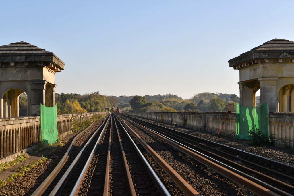The golden hour on the tracks of the Brighton Main Line with historic pillars either side