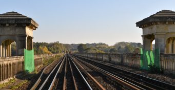 The golden hour on the tracks of the Brighton Main Line with historic pillars either side