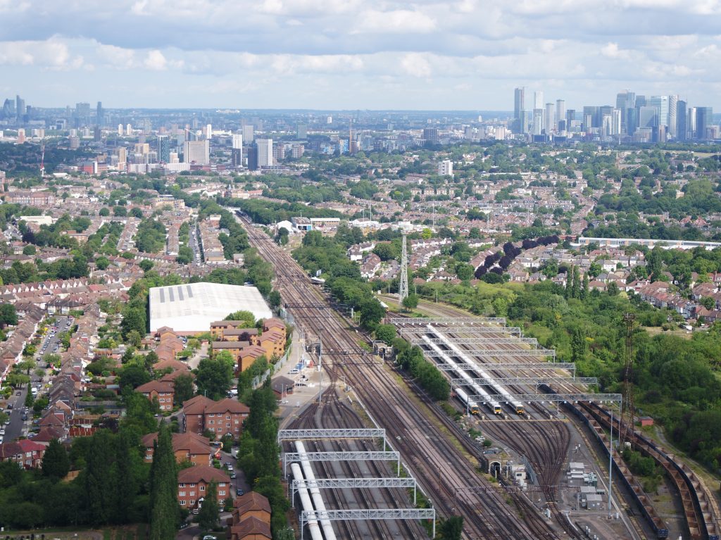 An aerial shot of tracks leading into London, with skyscrapers on the horizon.