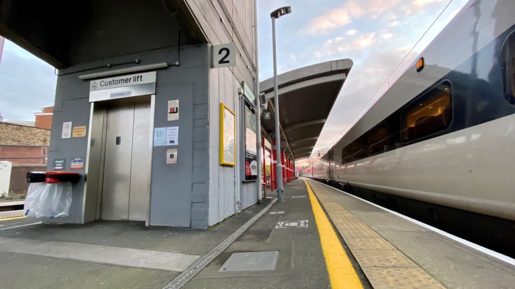 A station platform with customer lift, canopy and train