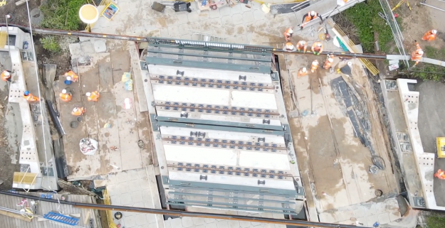 Aerial view of workers replacing bridge over a river, late May bank holiday, 2021, daytime