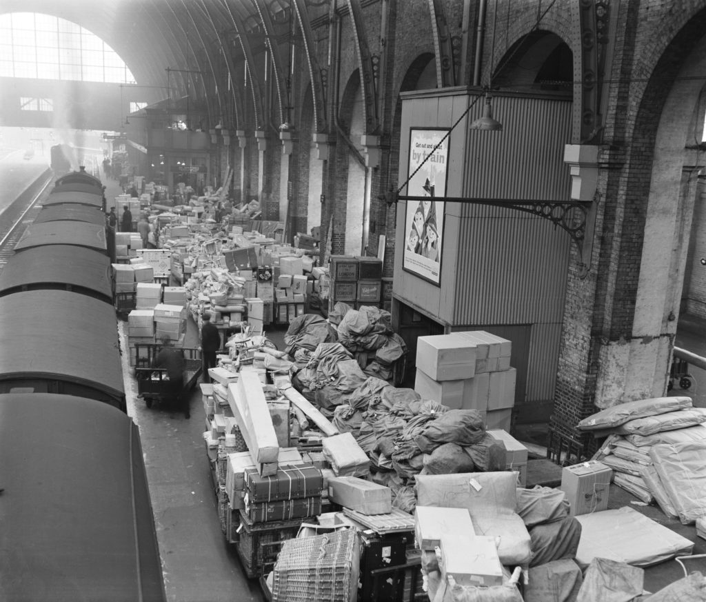 Black and white photo of a large volume of parcels along the platform at London King's Cross, Christmas 1960.