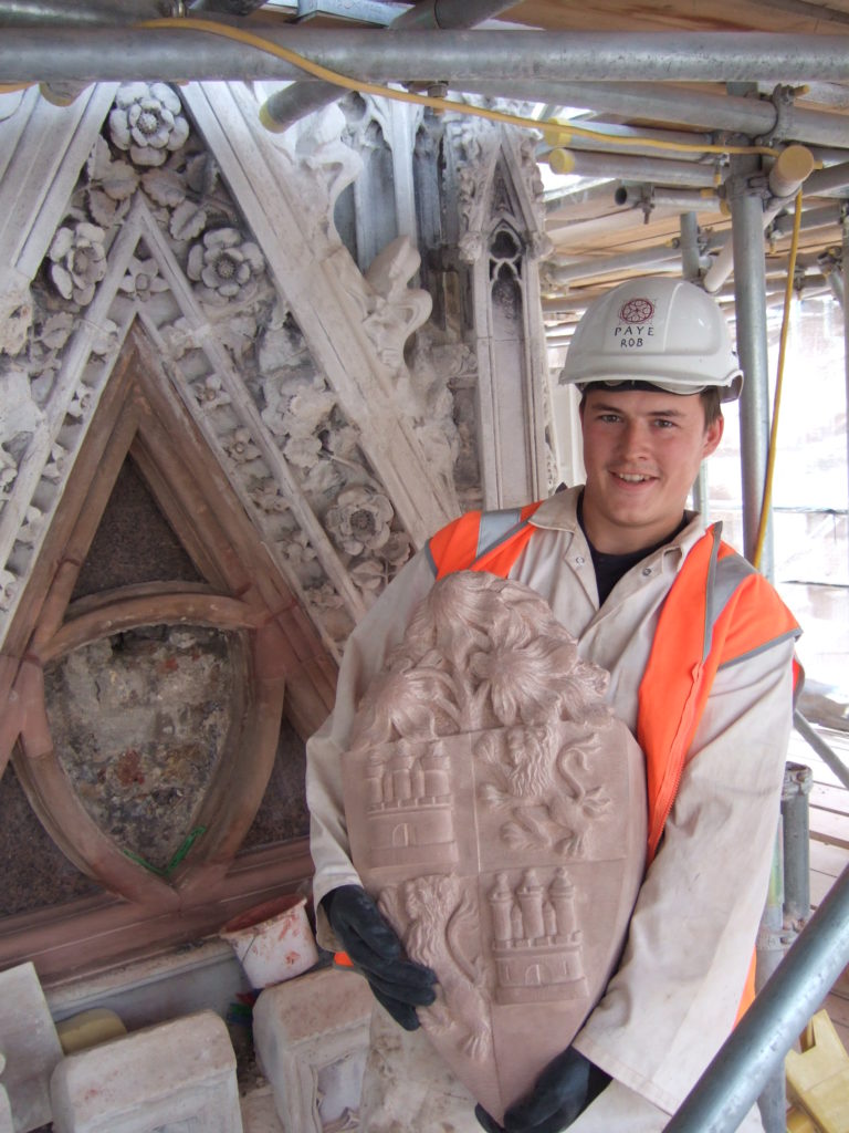 A workman holding the Eleanor Cross, up on the scaffolding