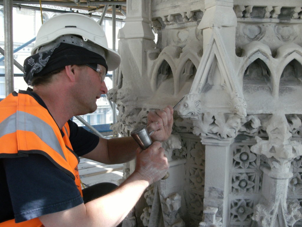 Close up of a workman restoring the details on the Eleanor Cross