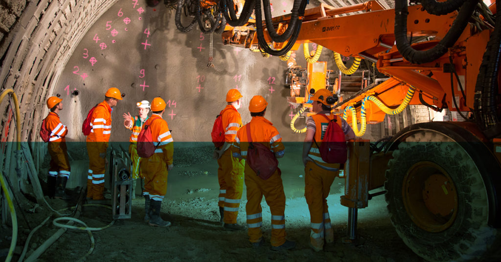 Group of Mechanical Engineering students on a year in industry are inside a large rail tunnel with huge machinery.