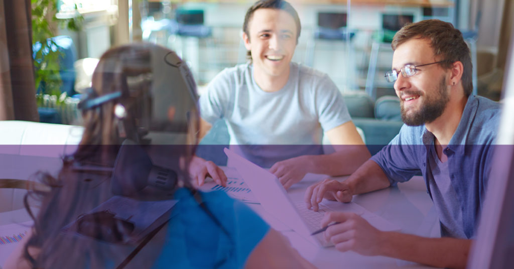 Three people on a finance summer placement laugh inside a glass-walled office.
