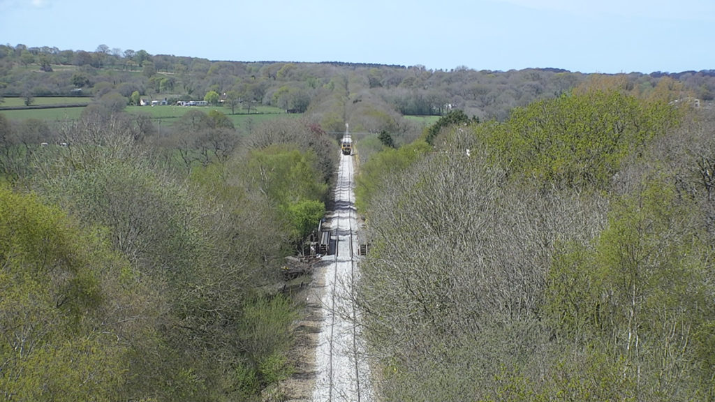 Aerial view of vegetation next to the railway line with a train coming down the track