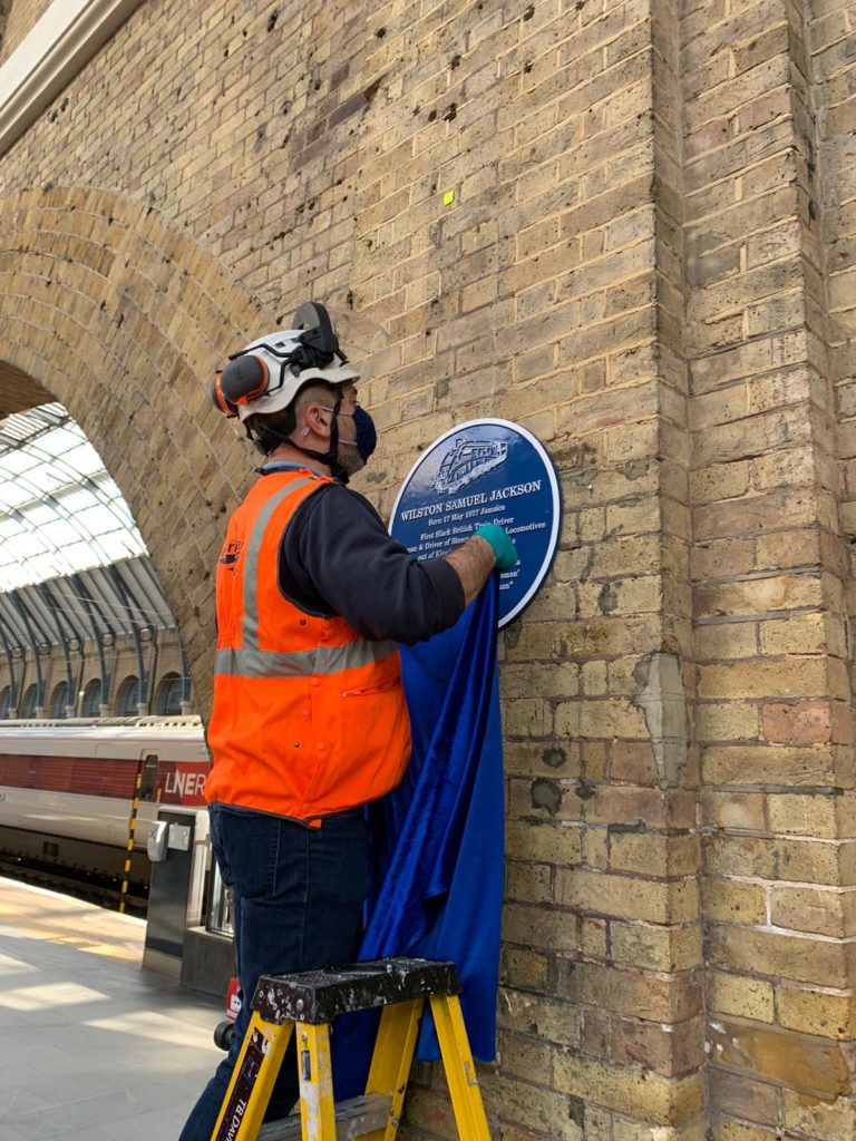 A Network Rail worker hangs the blue velvet curtain that will cover Wilston Samuel Jackson's blue plaque until its official unveiling