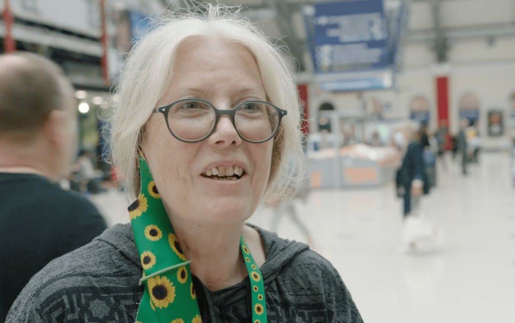 A female passenger wearing a sunflower lanyard and sunflower face covering at Liverpool Lime Street station