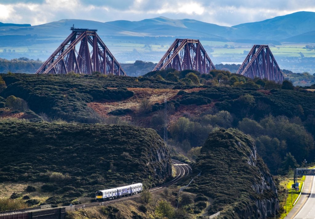 The electric Vivarail train with the Forth Bridge in the background