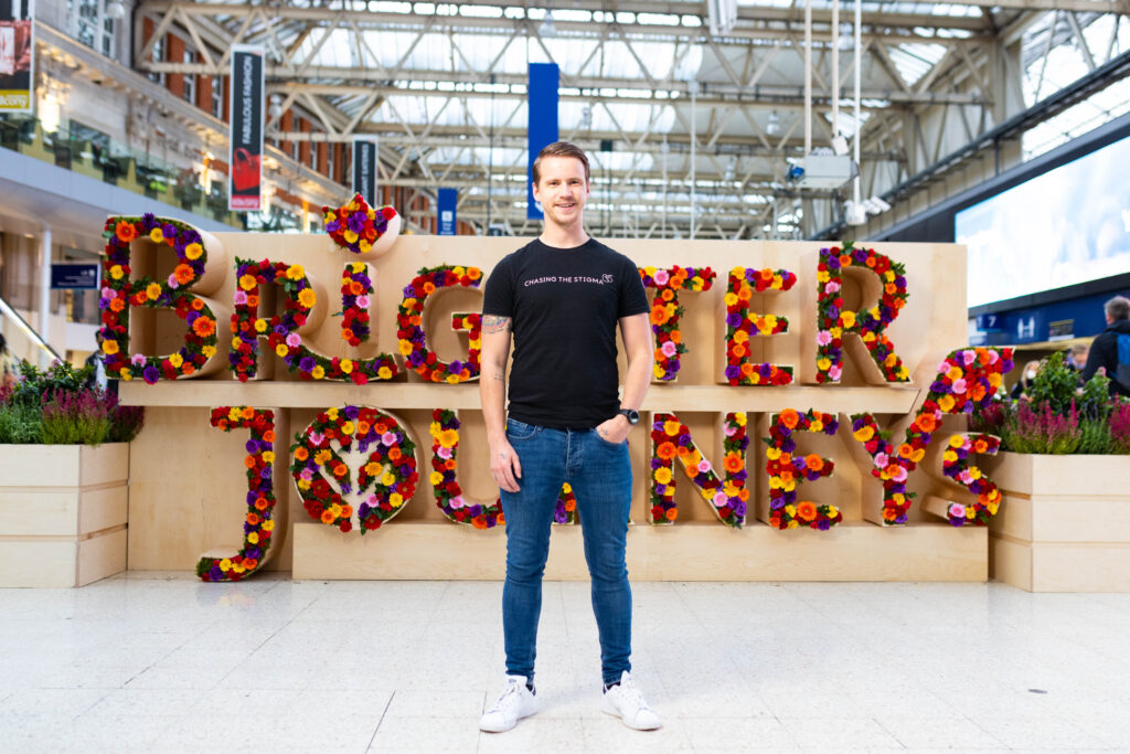 Jake Mills, Liverpool comedian and Chase the Stigma partner, in in front of Brighter Journeys flower/sensory installation.