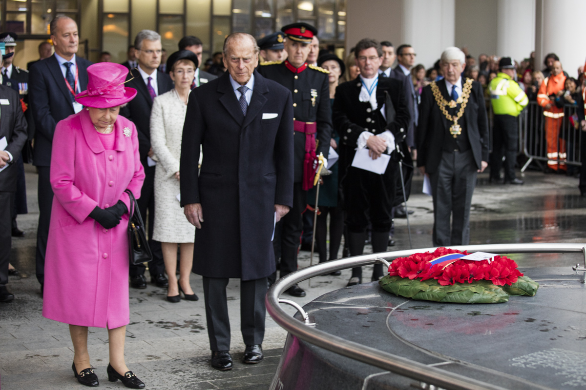 Her Majesty The Queen and His Royal Highness The Duke of Edinburgh walking through Birmingham New Street surrounded by royal escort.