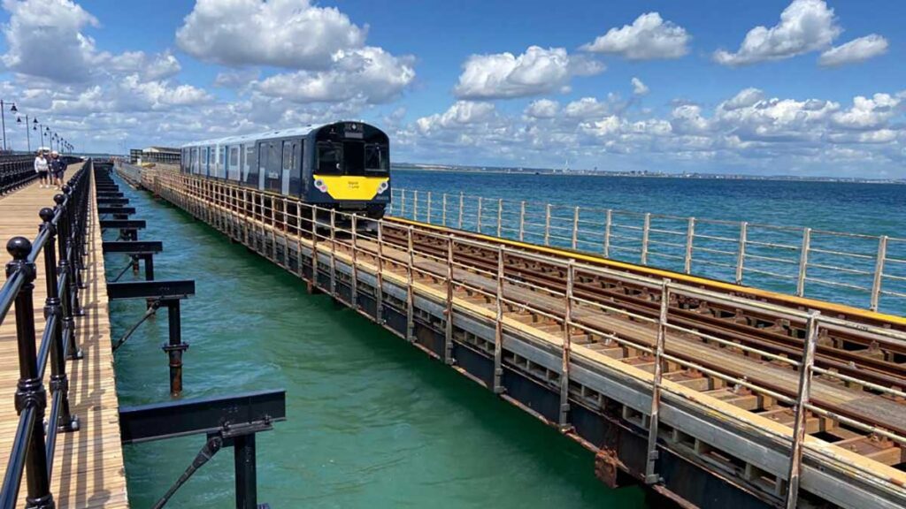 A train drives into Ryde Pier station on a sunny day.