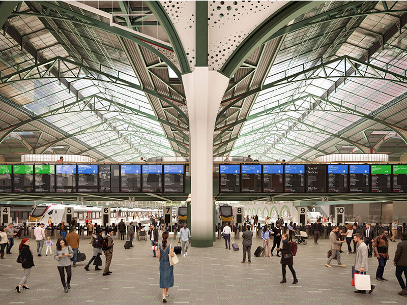 Artistic recreation of the proposed upgrade to the concourse of London Liverpool street bustling with a modern architectural design, featuring a large central pillar, arched green metallic roof, and electronic departure boards.