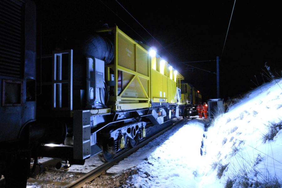 Winter development vehicle on the tracks with snow covering the hill next to the railway