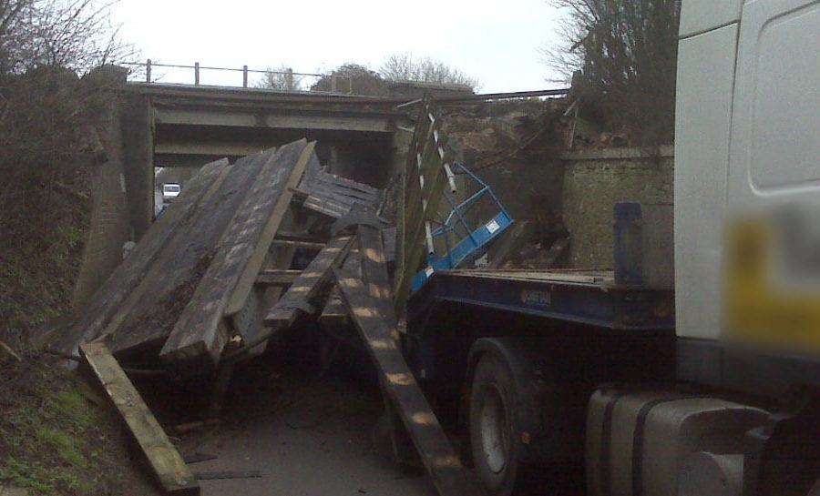 A load falling off the back of a lorry after hitting a bridge